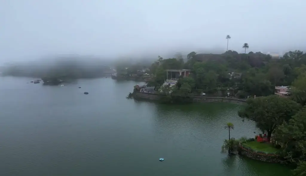 Foggy morning view of Nakki Lake surrounded by greenery in Mount Abu
