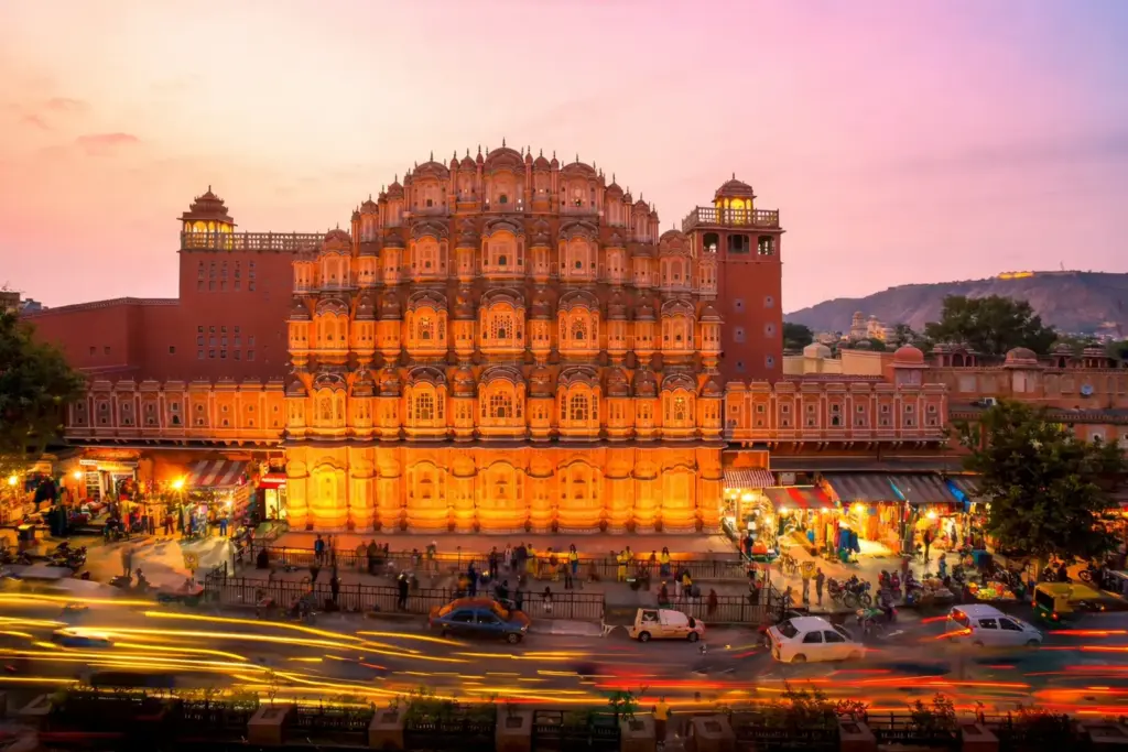 Hawa Mahal in Jaipur illuminated at sunset with busy city streets below